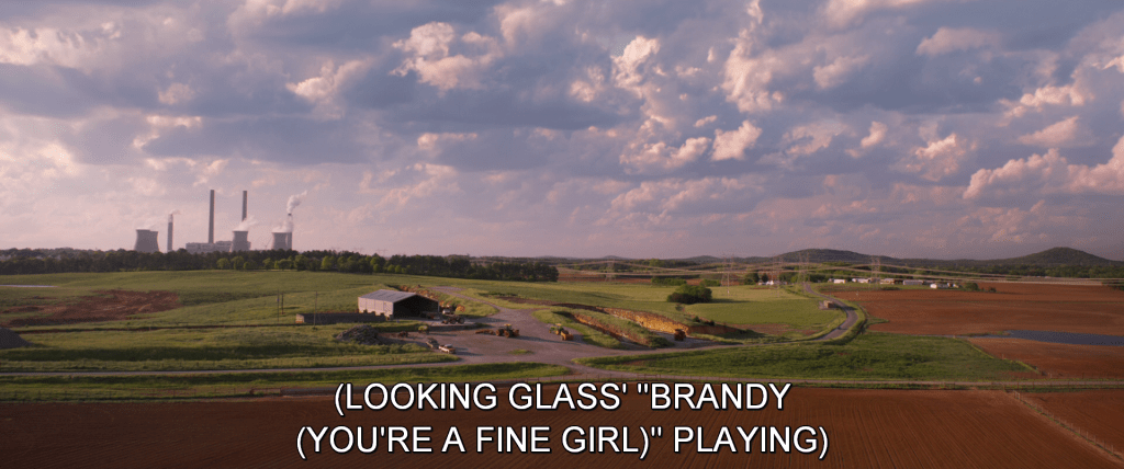 Establishing shot of a rural highway. Subtitles read, 