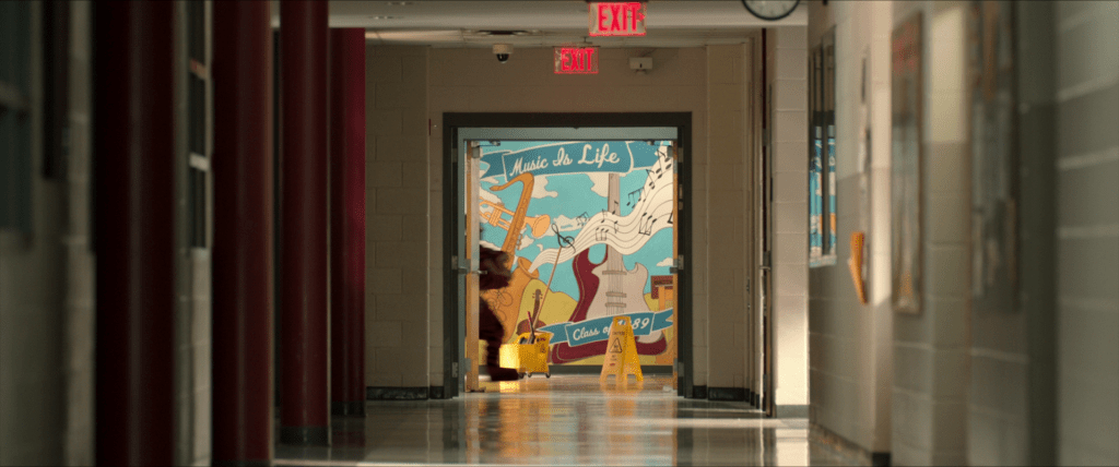 School hallway with a mural at the end. The mural depicts a saxophone, a trumpet, a violin, and an electric, with the phrase
